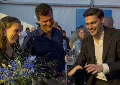 Goochelaar voert een interactieve kaarttruc uit voor lachende gasten aan een tafel tijdens een evenement in een tent.