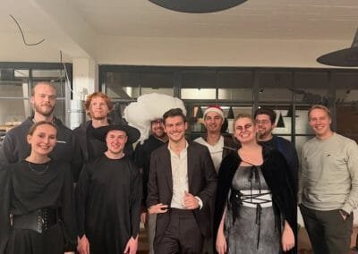Goochelaar poseert samen met een groep gasten na een optreden, waarbij sommigen verkleed zijn, in een gezellige indoor setting.